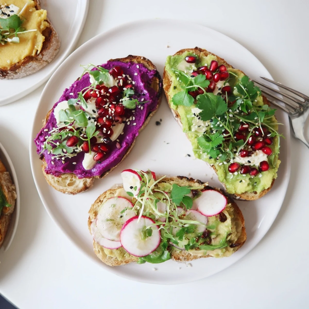 Colorful breakfast toasts stacked with creamy avocado and pomegranate seeds for flavor.