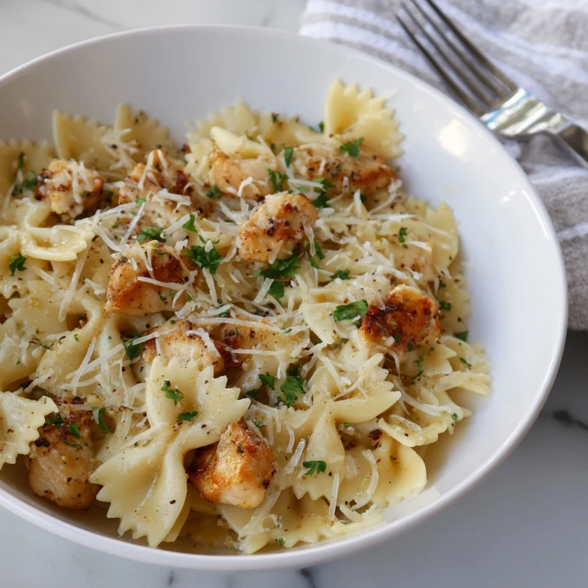 Creamy garlic butter sauce enveloping the Mozzarella Garlic Butter Chicken Bowties on a plate.  