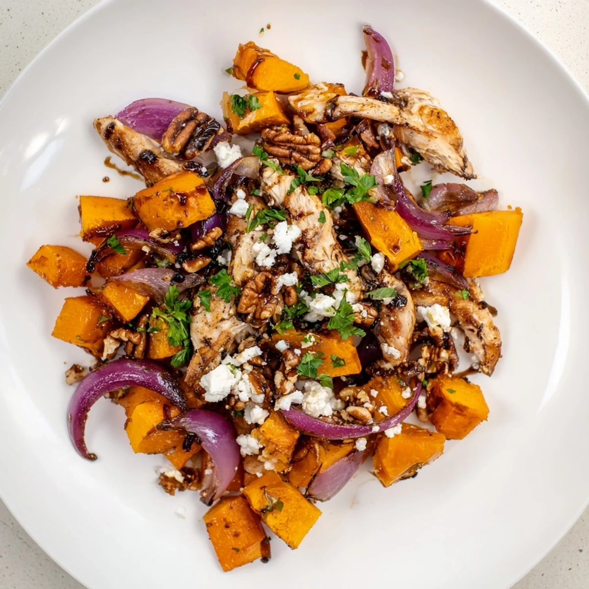 A sheet-pan filled with Roasted Chicken & Winter Squash Salad, mixed with fresh greens and a balsamic drizzle.