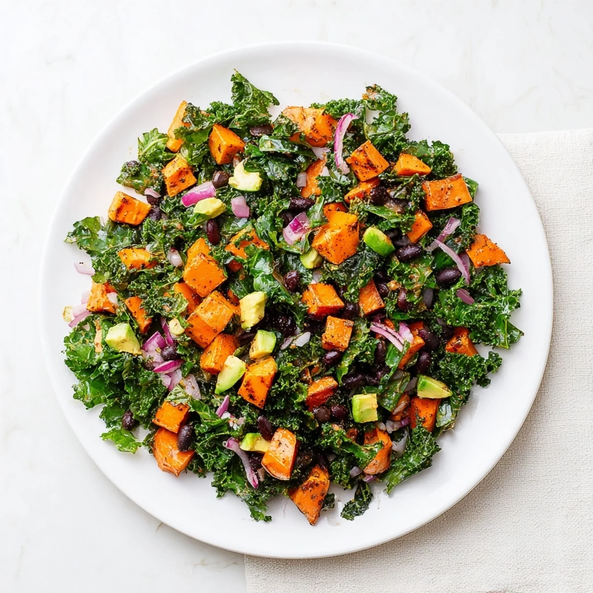 Close-up of a refreshing Massaged Kale Salad with vibrant sweet potatoes and creamy avocado.