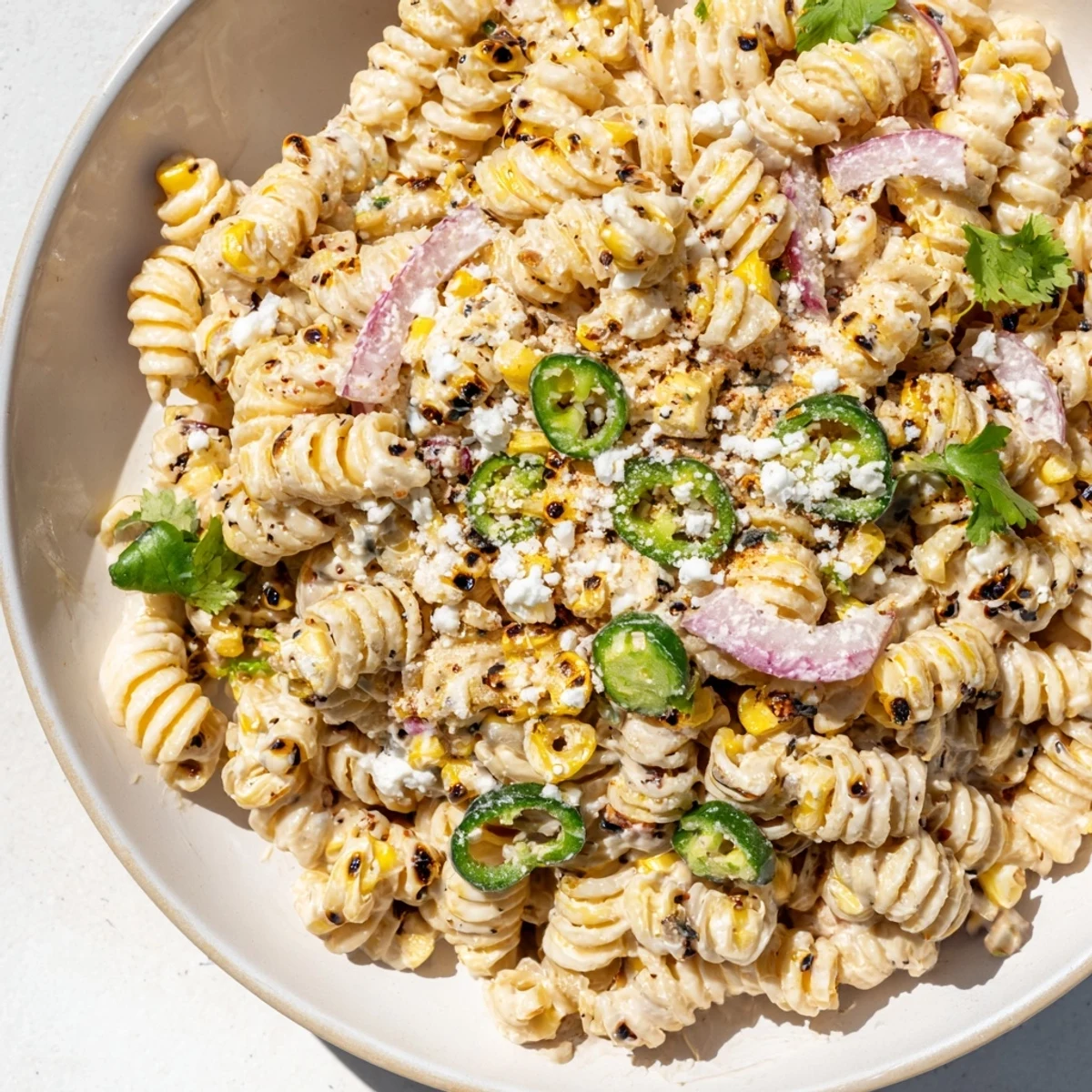 Freshly made Creamy Street Corn Pasta Salad, perfectly chilled and ready to serve with lime wedges.