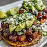 Black Bean and Sweet Potato Tostadas are garnished with creamy avocado slices and crumbled feta cheese.
