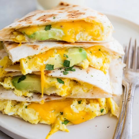 Stacked Avocado Egg Cheddar Quesadillas, cut into wedges, showing layers of vibrant fillings.