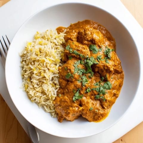 Delicious butter chicken in creamy tomato sauce served over fluffy rice pilaf.  