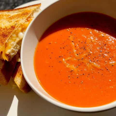 Melted cheddar cheese oozing from a grilled cheese sandwich, perfect with creamy Tomato Soup.