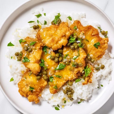Warm Express Chicken Piccata Rice Bowl, steaming with fluffy rice beneath a creamy, flavorful piccata sauce.
