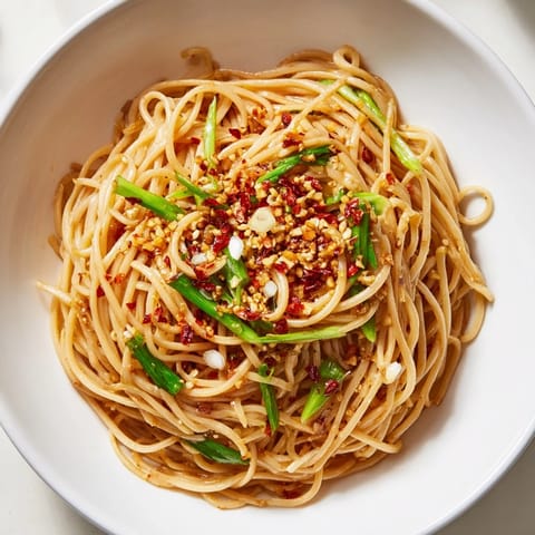 A close-up of Garlic Chili Oil Noodles, showcasing the spicy, red chili oil coating.