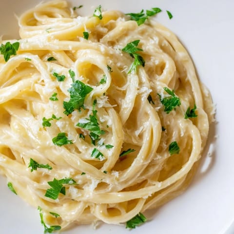 A bowl of steaming sriracha honey pasta with a glossy, creamy sauce and red pepper flakes.
