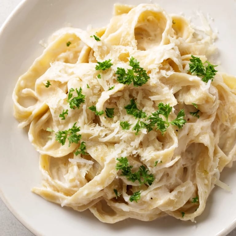 A visually appealing photo of Pasta Alfredo Cottage Hack, swirled on a plate and garnished with parsley.