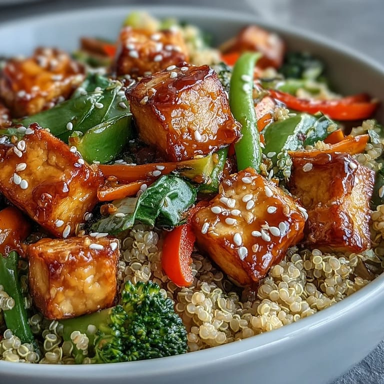 Glistening quinoa vegetable teriyaki bowl served with sesame seeds and green onions.