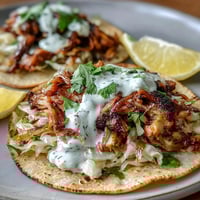 Roasted chicken cabbage tacos with zesty lemon crema and fresh cilantro on warm tortillas.  